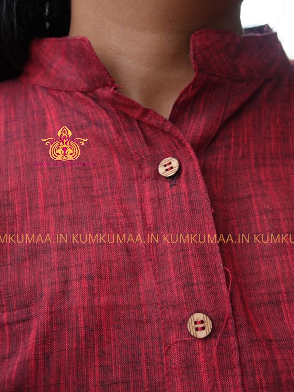Red checkered shirt with a logo and buttons, featuring the brand 'KUMKUMAA'.